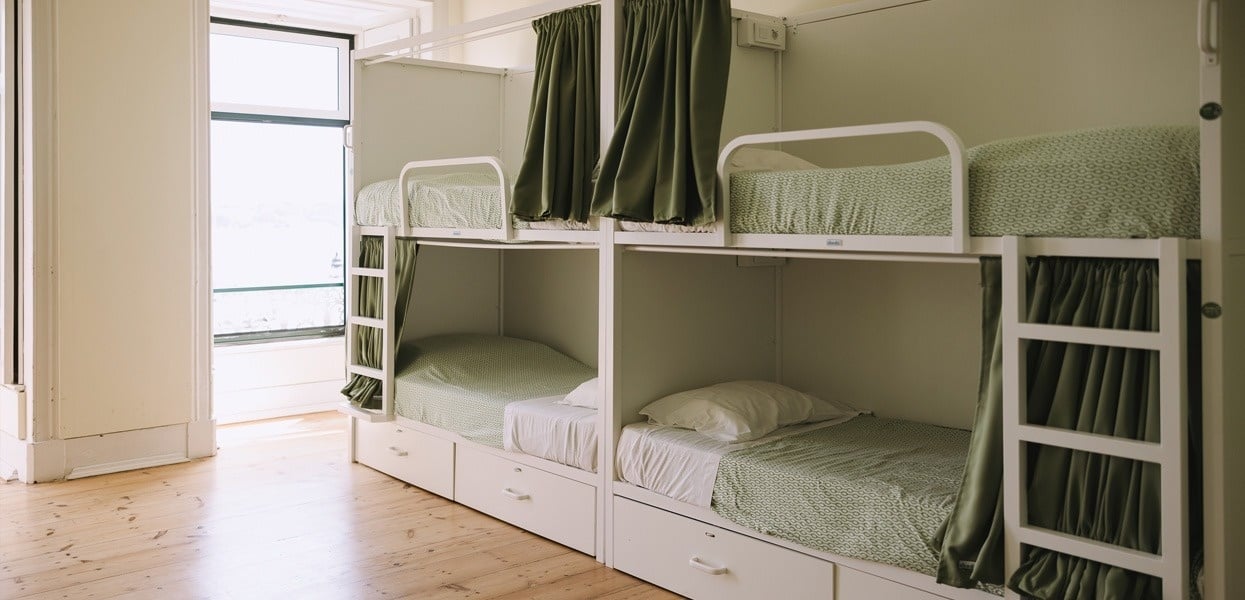 una habitación llena de literas con cortinas verdes