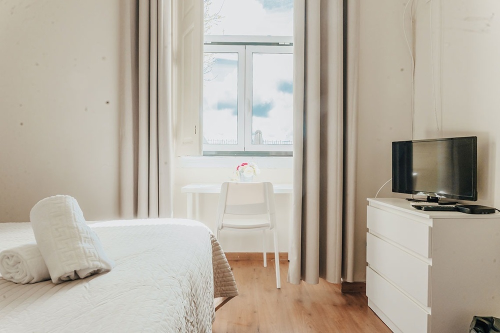 um quarto com cama e televisão e uma janela