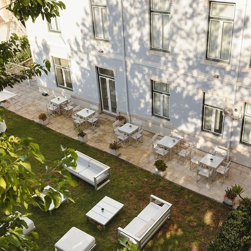 a white building with tables and chairs in the backyard