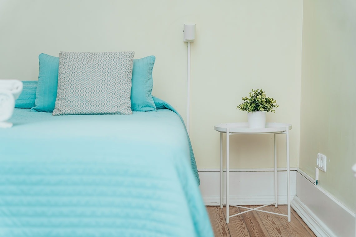a white table with a plant on it sits next to a bed