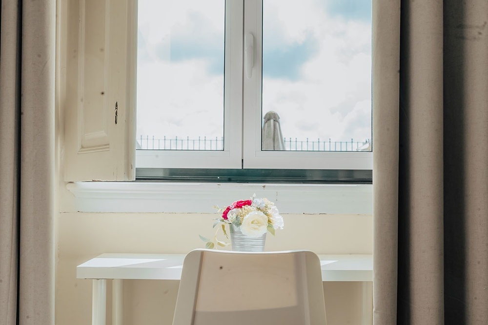 um vaso de flores está sobre uma mesa em frente a uma janela