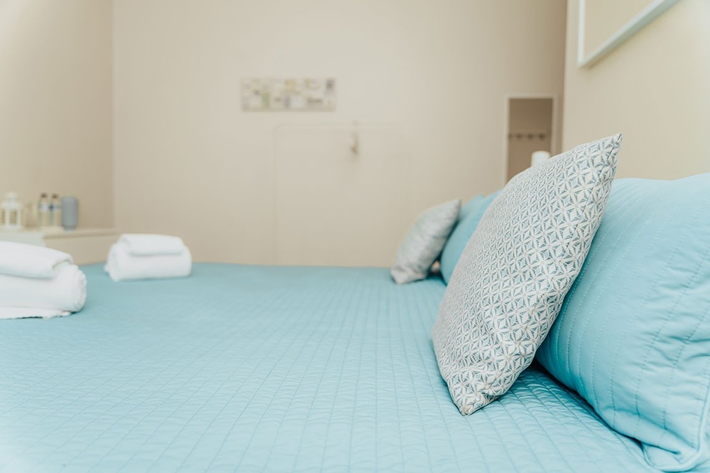 uma cama com cobertor azul e almofadas azuis