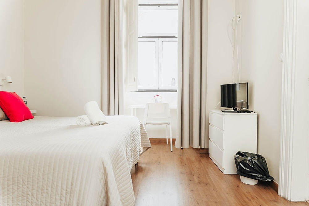 um quarto branco com uma cama e uma televisão