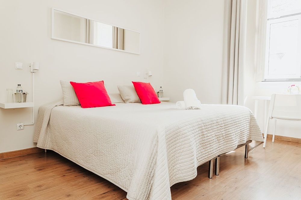 uma cama branca com almofadas vermelhas em um quarto