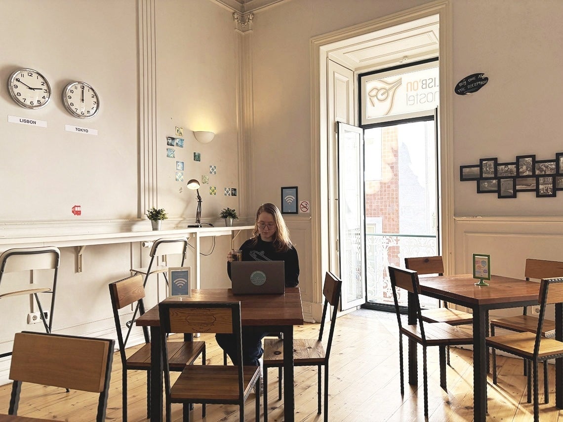 Área de coworking do hostel em Lisboa: hóspede trabalha no laptop com Wi-Fi.
