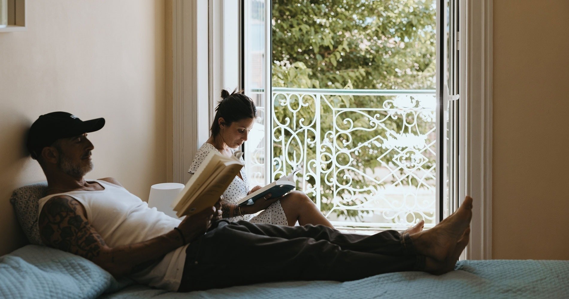 un hombre y una mujer están acostados en una cama leyendo libros