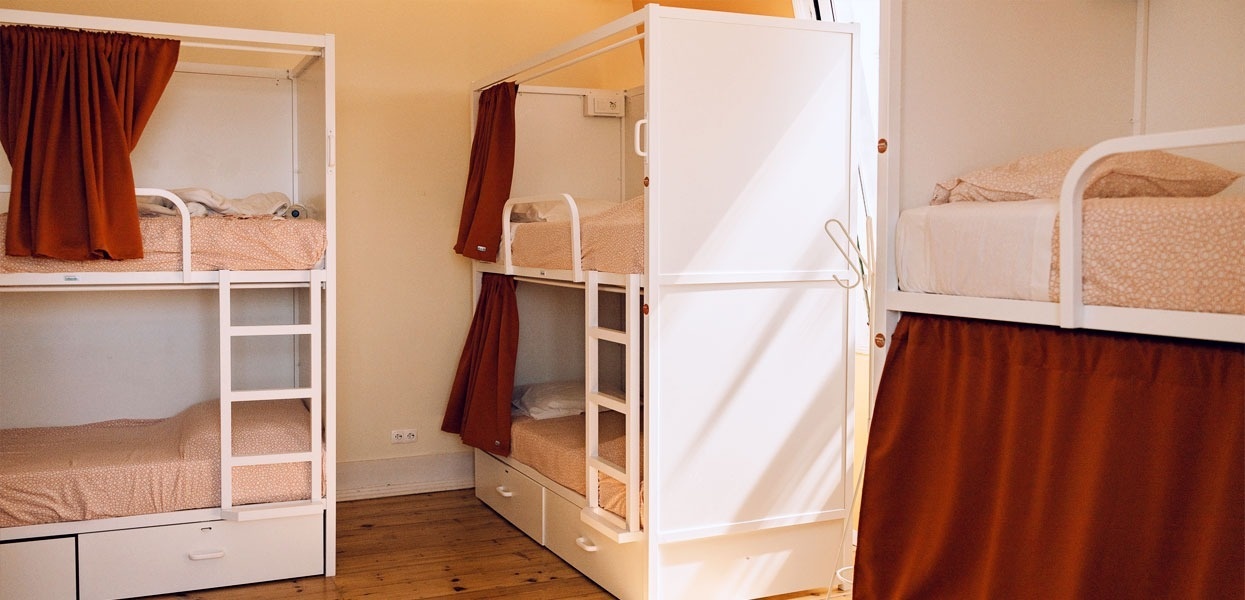 tres literas en una habitación con cortinas rojas