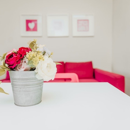 a bucket of flowers sits on a table in front of a pink couch