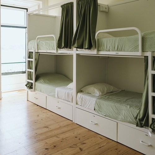 a row of bunk beds with green curtains and white sheets