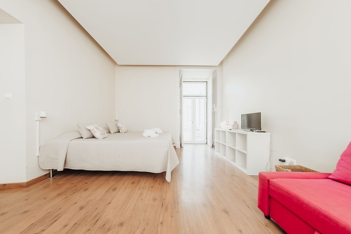 a bedroom with a bed and a red couch