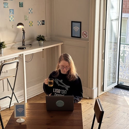 Hostel Lisb'on: hóspede com laptop e chá. Wifi, espaço de trabalho confortável e varanda.