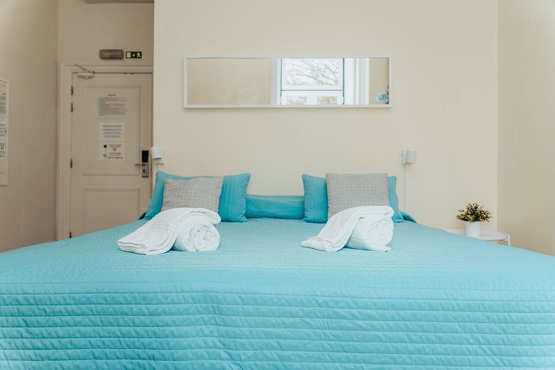 a bed with a blue blanket and white towels on it