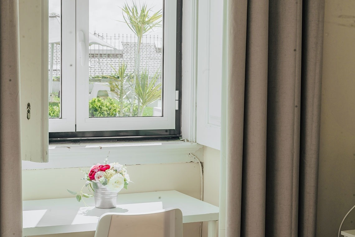 a vase of flowers sits on a desk in front of a window