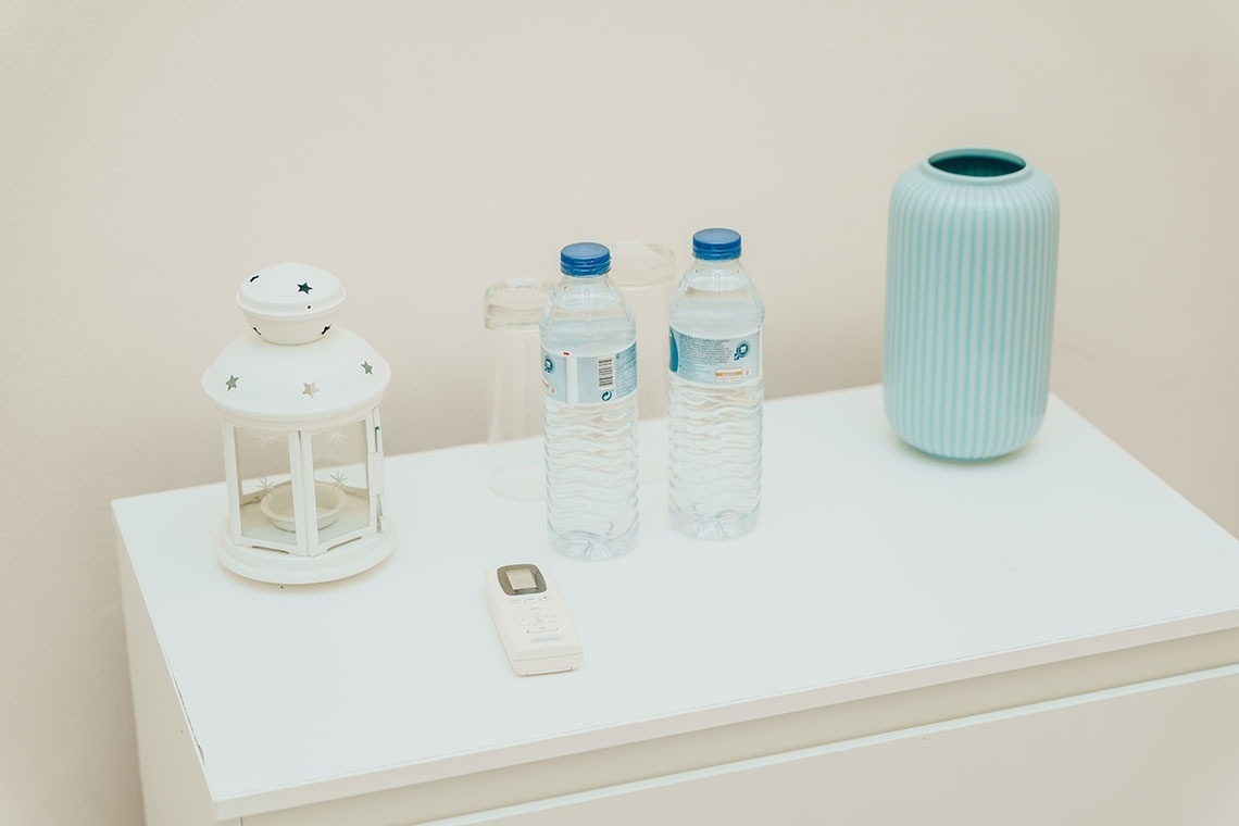 two bottles of water sit on a table next to a vase