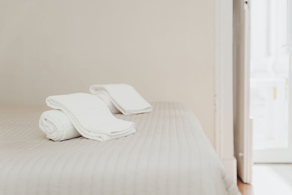 duas toalhas brancas são dobradas em cima de uma cama