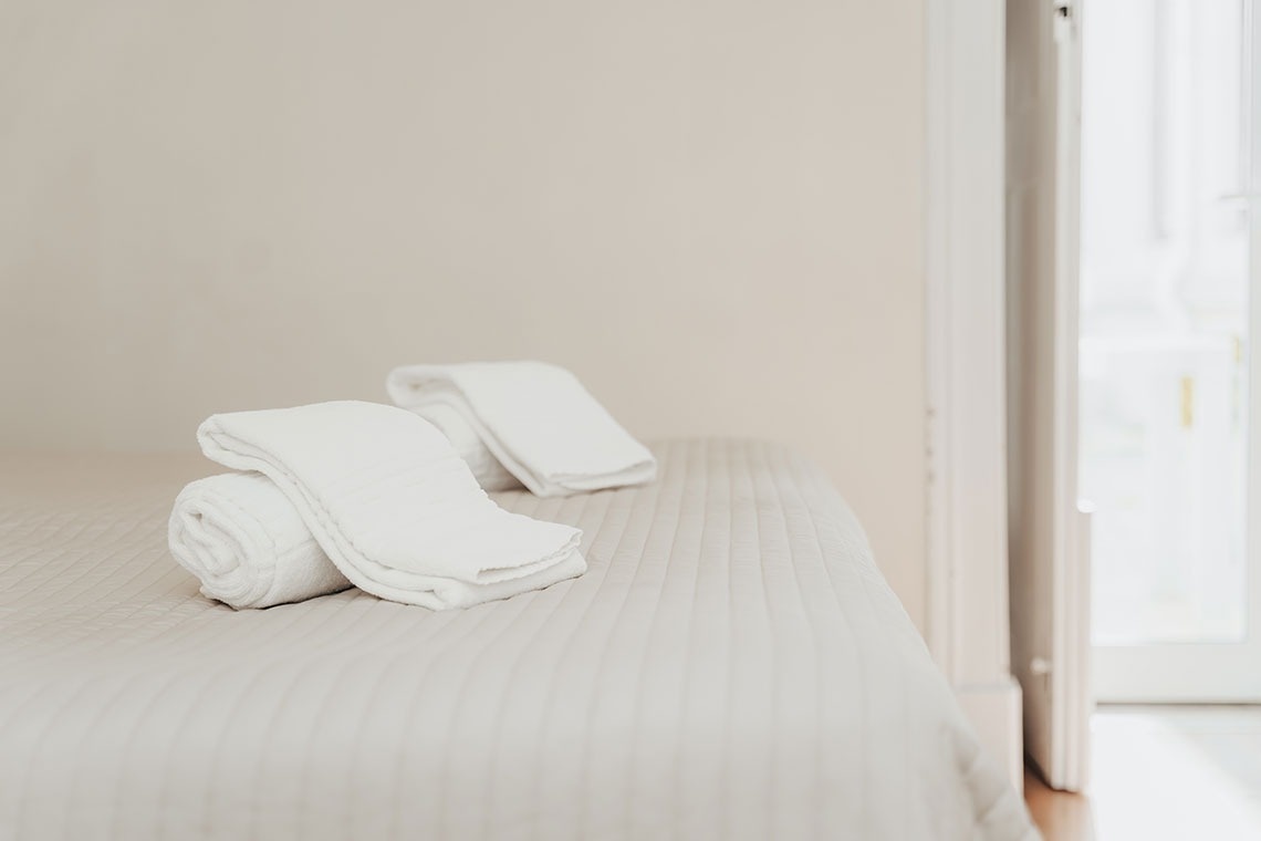 two white towels are rolled up on a bed