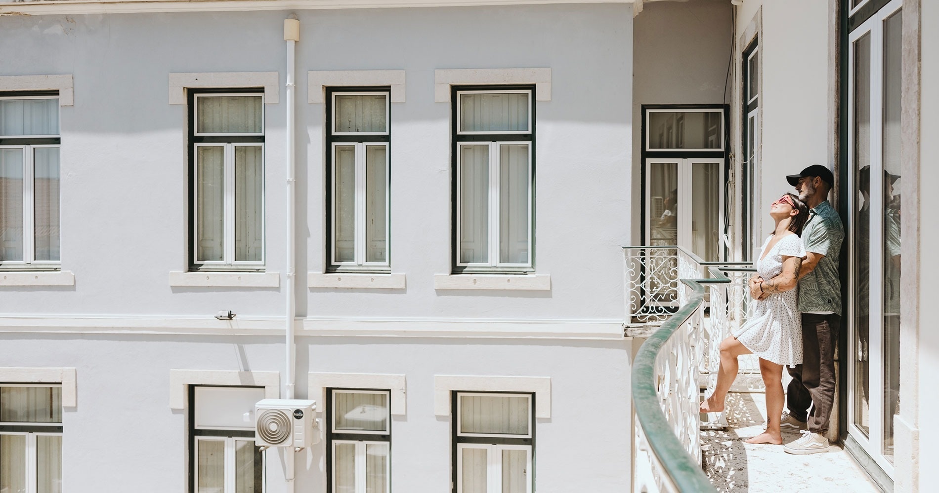 un hombre y una mujer se paran en un balcón mirando por la ventana