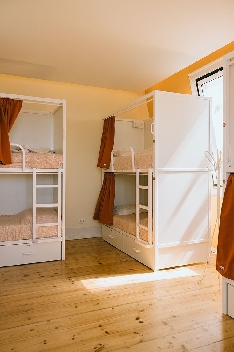 three bunk beds in a room with orange curtains