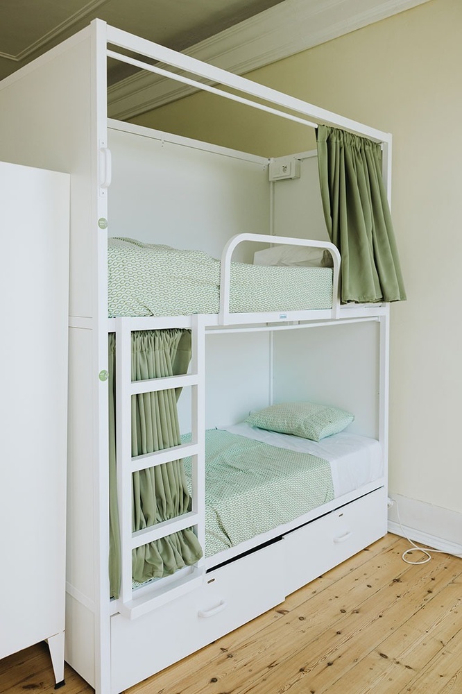 uma cama de beliche branca com cortinas verdes