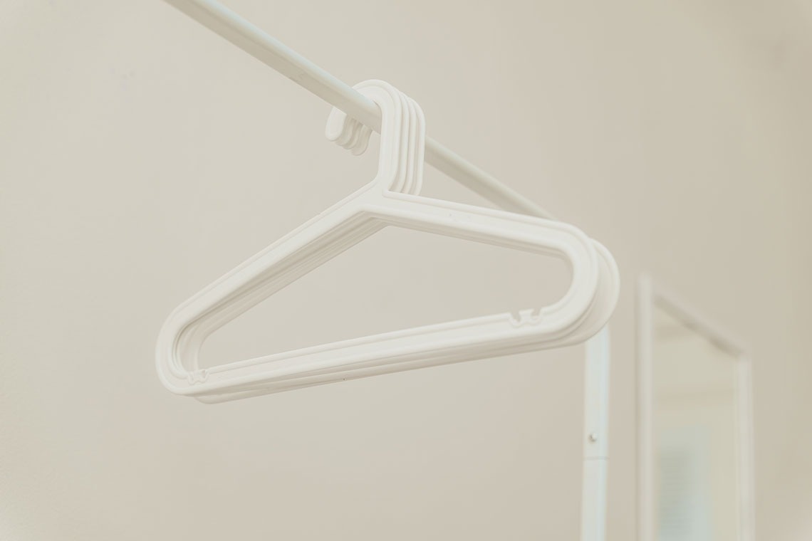 a white plastic hanger hangs from a white railing