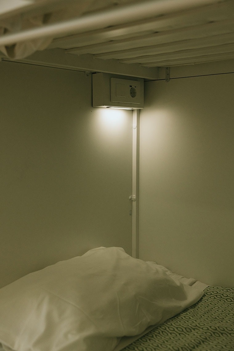a bed with a white pillow and a light underneath it