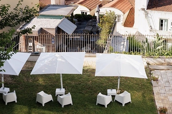 quatro cadeiras e quatro guarda-chuvas brancos estão na grama