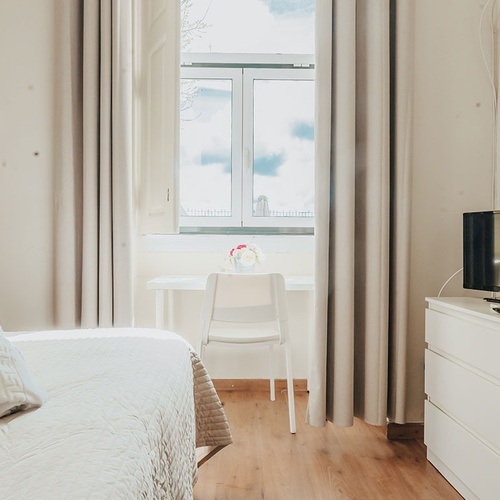 a bedroom with a bed a desk and a television