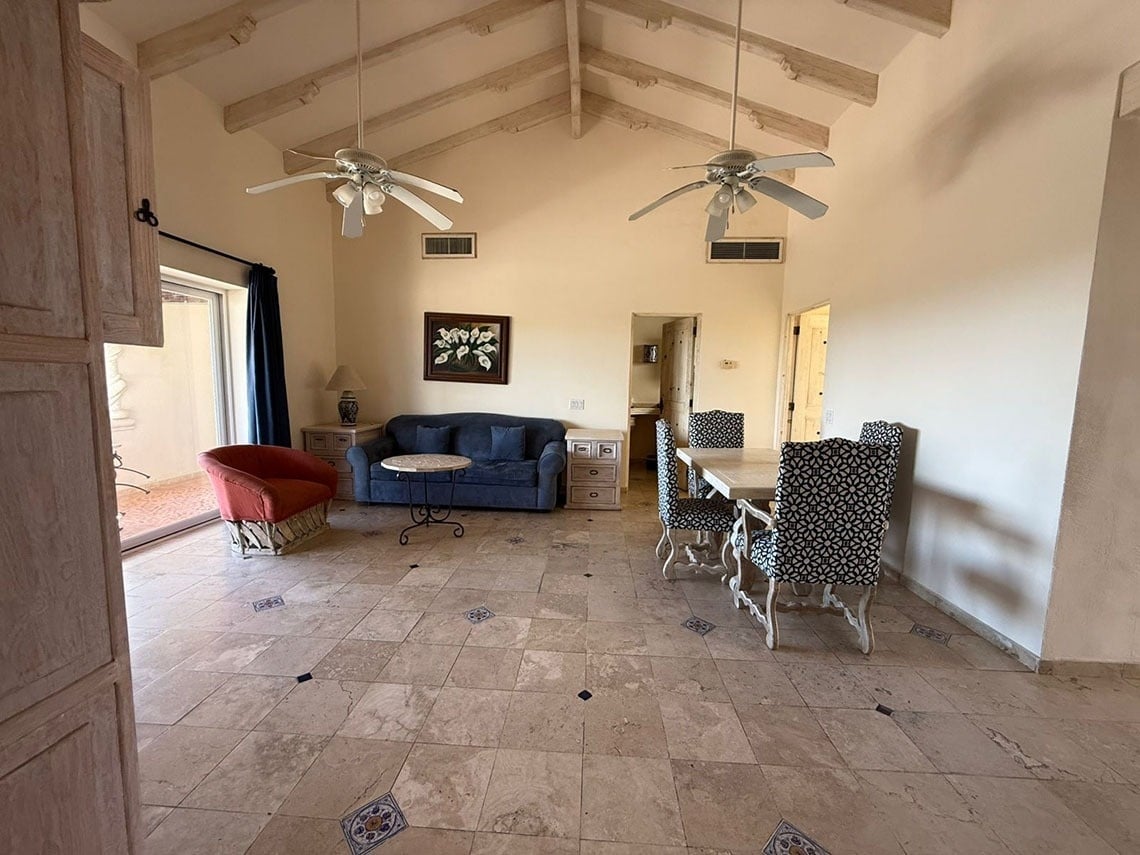 Sala de estar y comedor de estilo tradicional con techos abovedados, suelo de baldosas y muebles combinados.