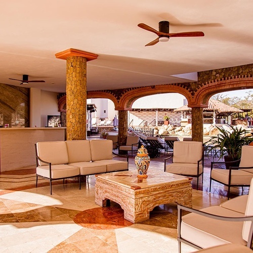 Un acogedor vestíbulo de hotel con área de recepción y zona de estar, abierto a un paisaje exterior a través de arcos de ladrillo.