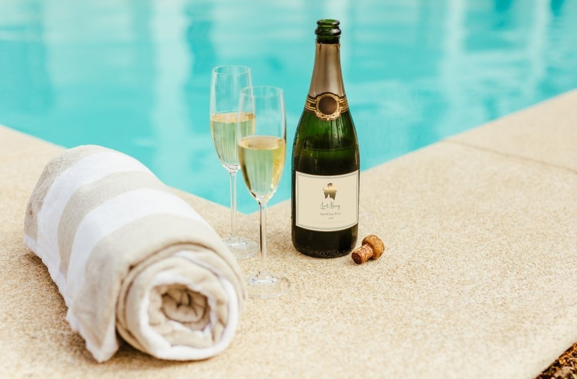 Una terraza al aire libre decorada con guirnaldas de luces ilumina cómodos asientos y mesas de comedor al atardecer, con un campo de golf y una piscina al fondo.