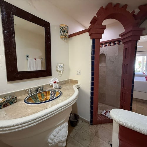 Una vista de un cuarto de baño ornamentado con un lavabo vibrante y un arco que lleva a una habitación.