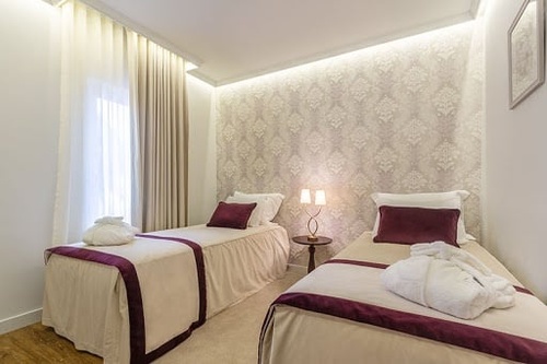 Elegant hotel room with two twin beds, white robes, and ambient lighting. Perfect Luna Corporativa.