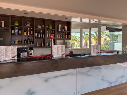 Balcão elegante do Luna Corporativa com bebidas e vista para palmeiras.