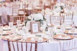 Table setting for Luna Corporativa event: gold plates, white hydrangeas, table number 21.