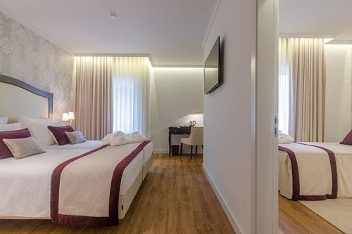 Elegant hotel room with two beds, modern decor, and a desk area. Luna Corporativa