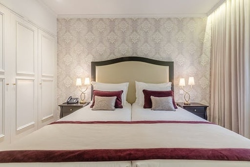 Luxurious hotel bedroom with a large bed, elegant wallpaper, and bedside lamps. Luna Corporativa