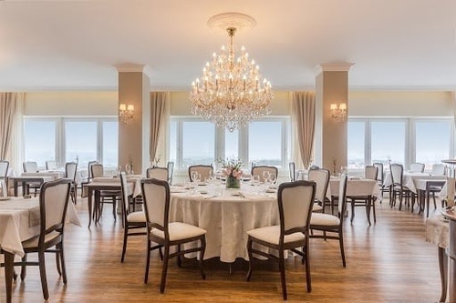 Elegant hotel dining room with classic decor, sparkling chandeliers, and large windows.