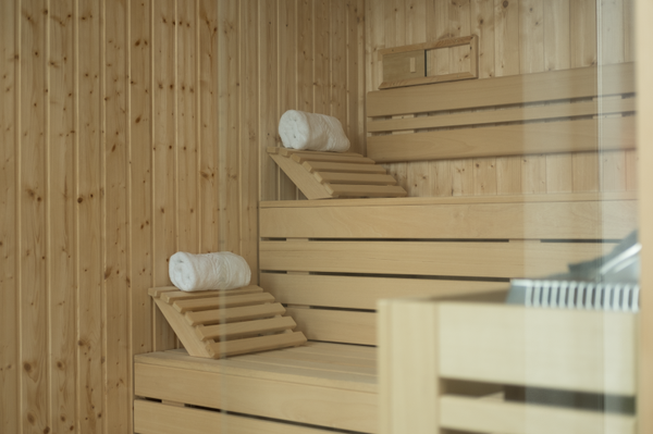 Luna Corporativa: Interior of a wooden sauna with rolled towels on benches.