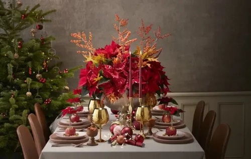 uma mesa de jantar decorada para o natal com poinsettia vermelha e velas .