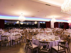 Elegante banquete en Luna Corporativa con mesas redondas, sillas de madera y candelabros.