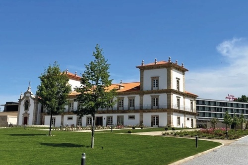 a large white building with a red roof is surrounded by trees