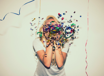 Uma pessoa no meio da imagem a soprar confetes