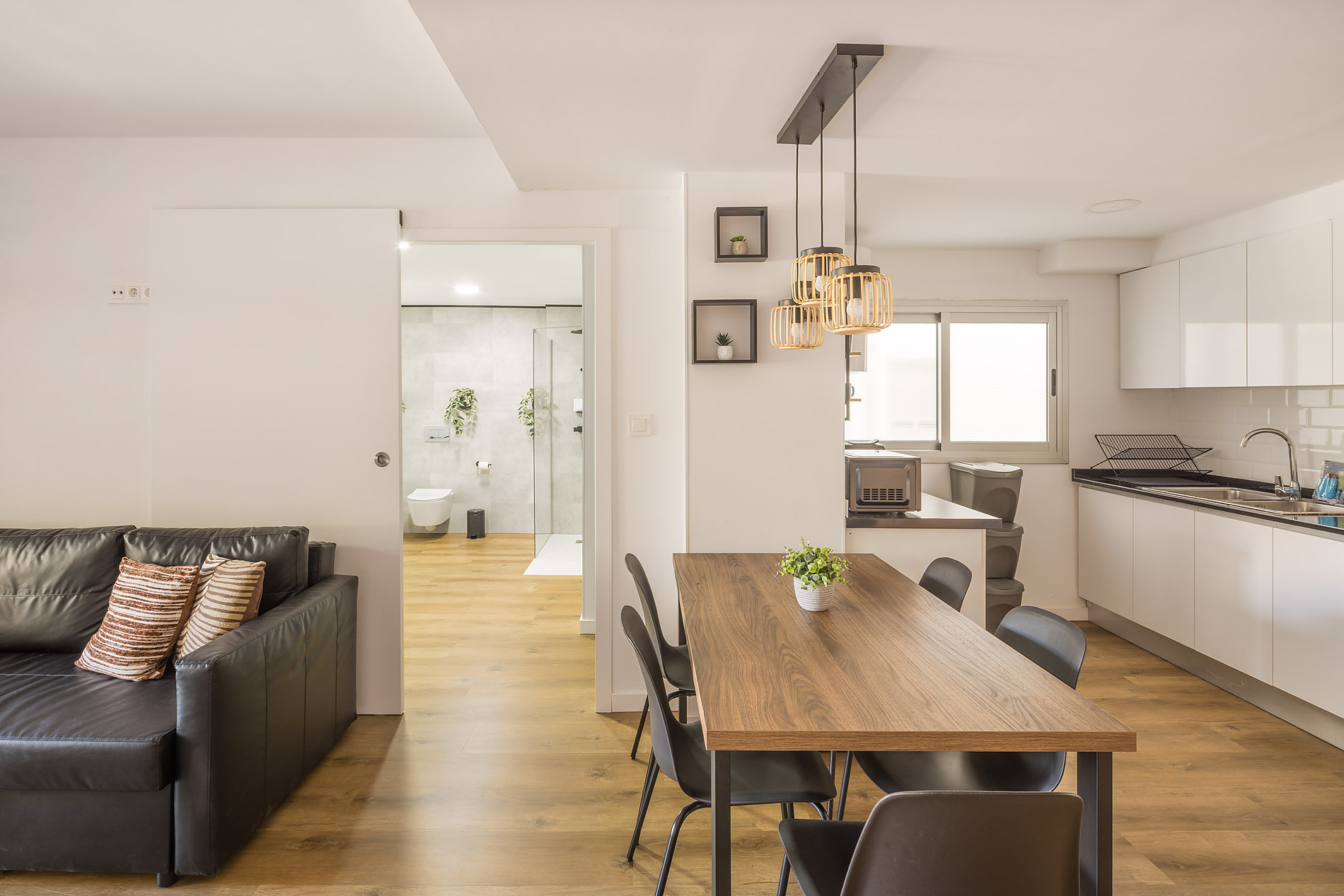Modern living room with leather sofa, dining table, and kitchen view. Macflats: Ciudad de las ciencias.