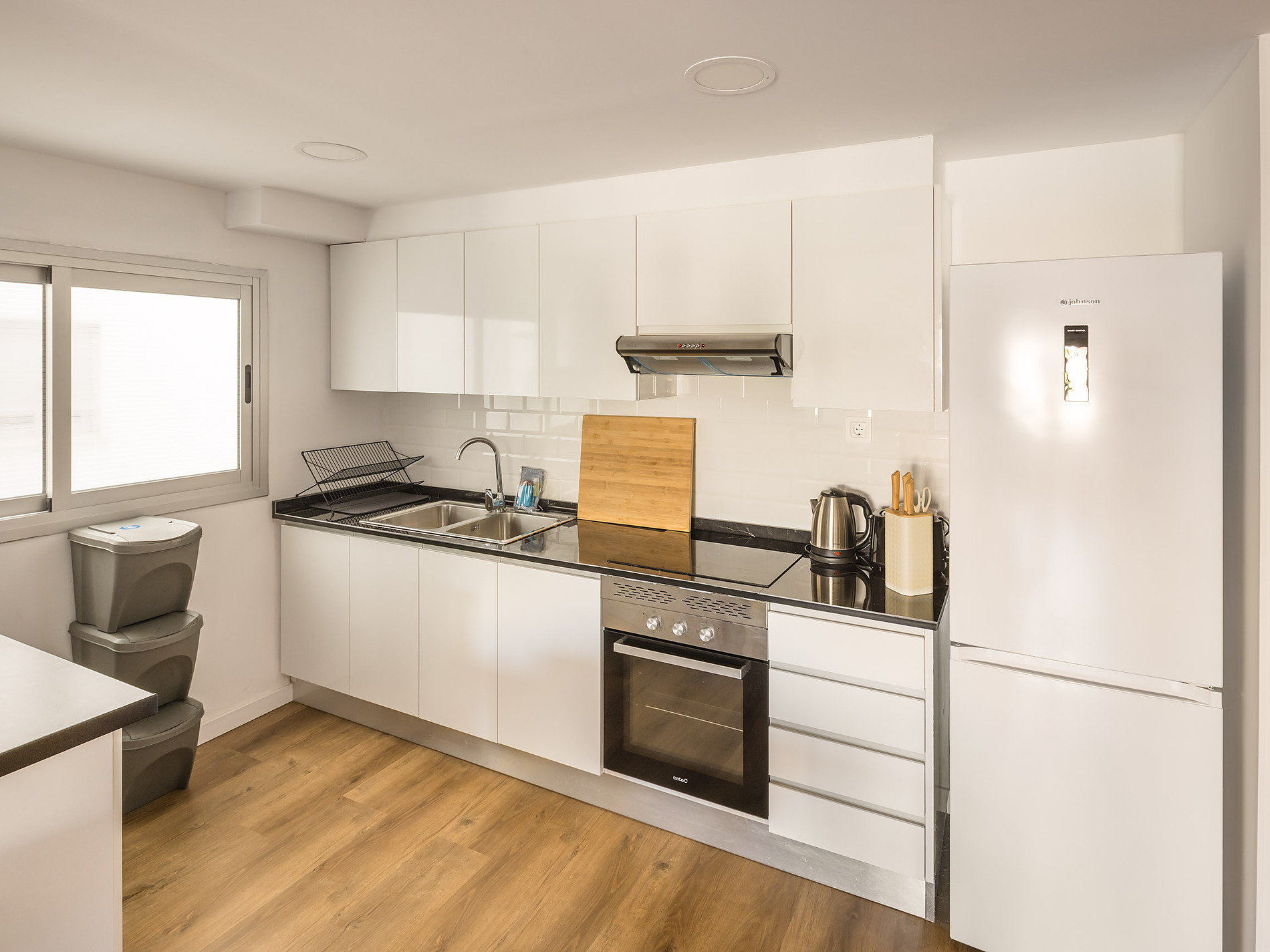 Modern white kitchen with refrigerator, oven, and stovetop. Macflats: Ciudad de las ciencias.