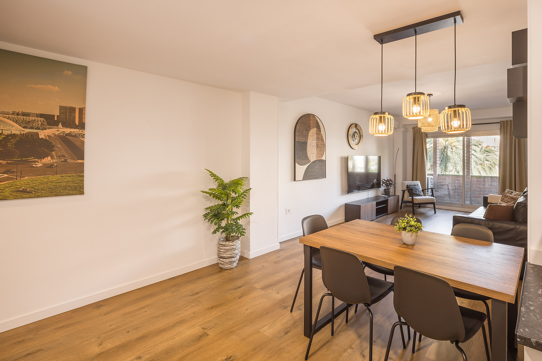 Modern dining area and living room in a hotel, featuring a wooden table, chairs, and artwork. Macflats: Ciudad de las ciencias