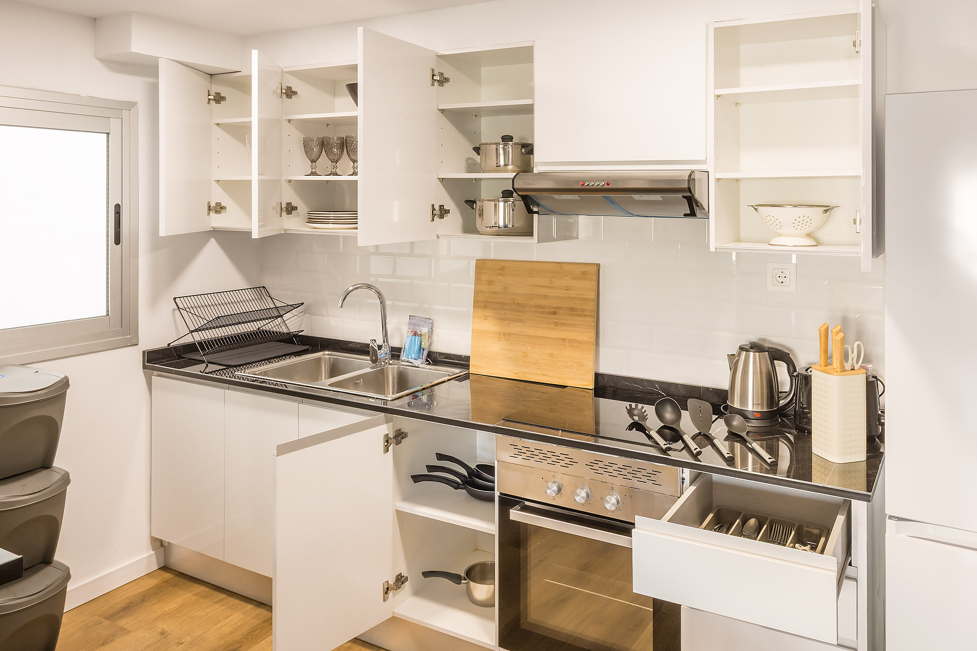 Modern hotel kitchen with stovetop, oven, sink, and cabinets. Macflats: Ciudad de las ciencias