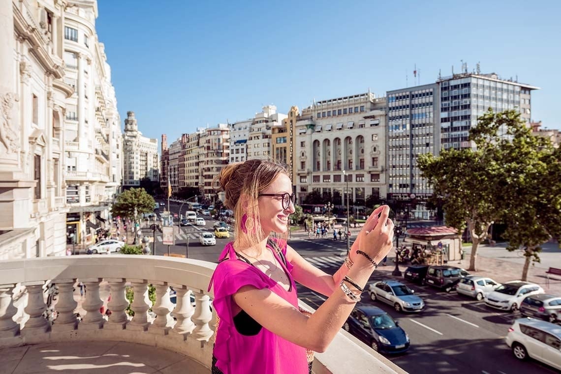 una mujer toma una foto de la ciudad con su teléfono celular