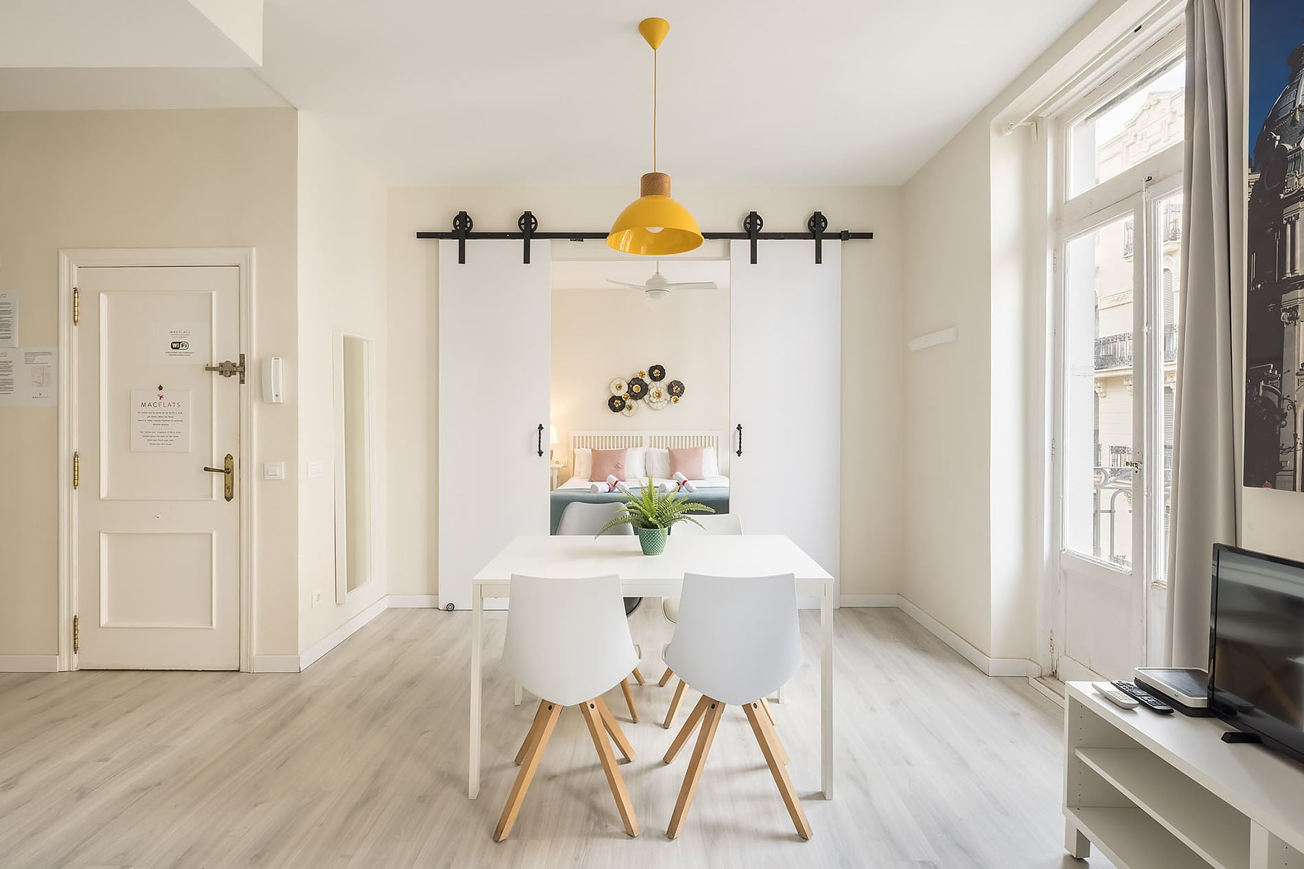 Macflats: Corporativa: comedor moderno con sillas blancas y mesa, junto a habitación con cama matrimonial.