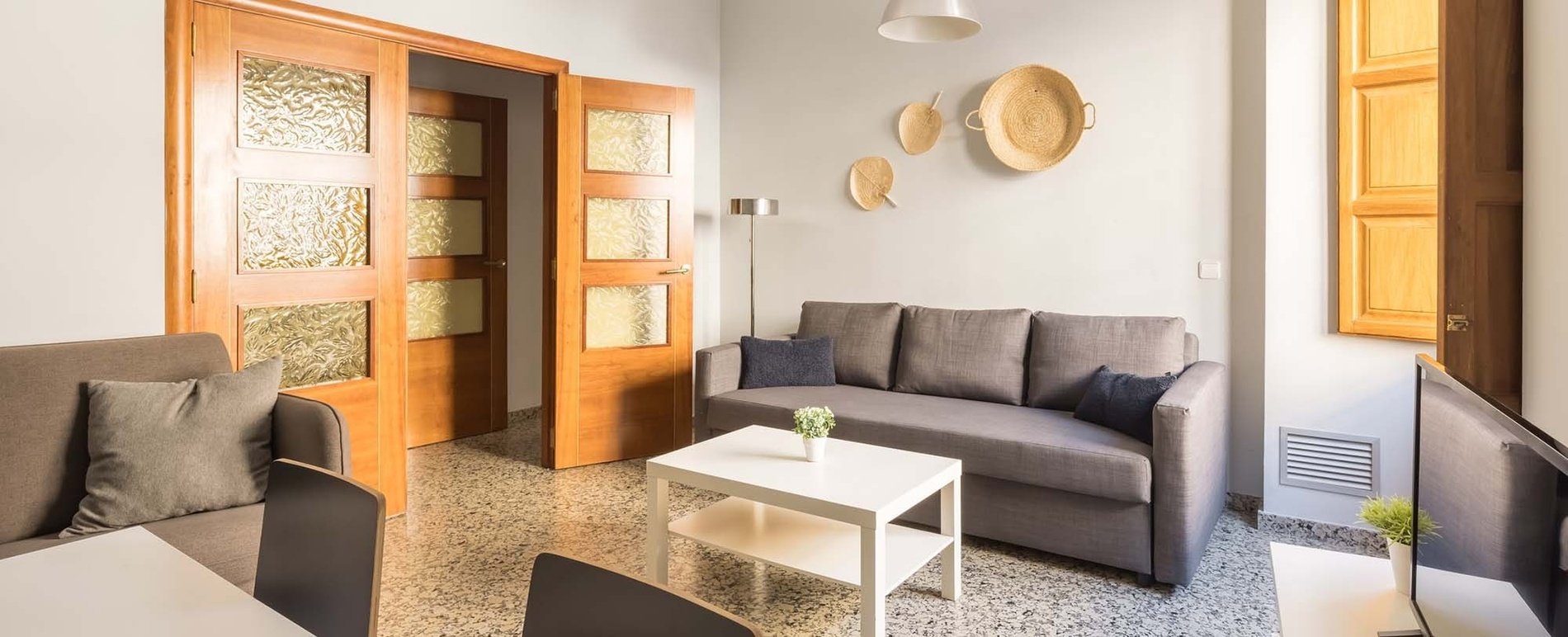 una sala de estar con un sofá gris y una mesa blanca