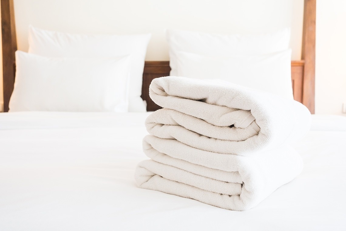 una pila de toallas blancas sobre una cama blanca